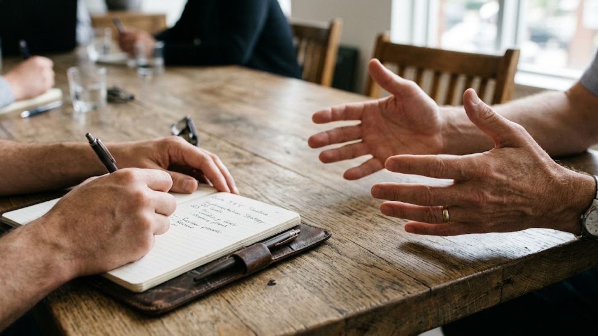 Two people in a focused working conversation across a table.